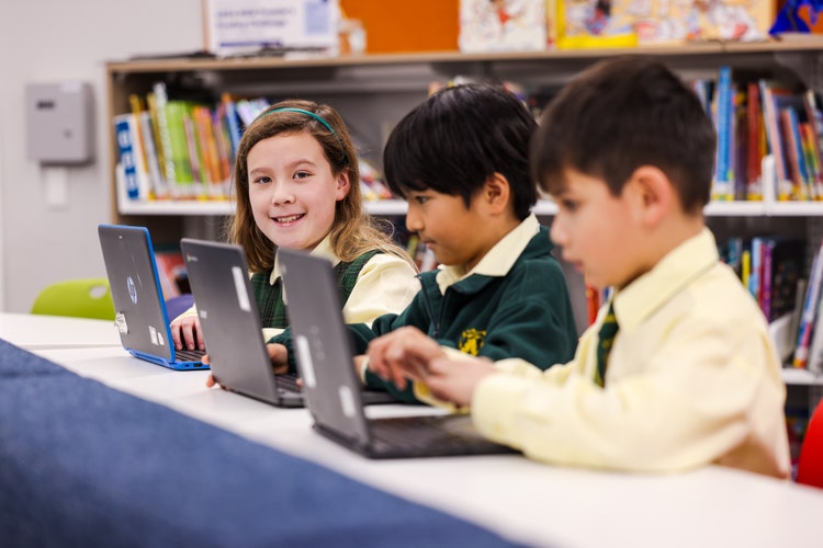 3 students on laptops in the library
